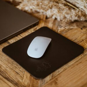 skórzana podkładka pod myszkę leży na stole obok laptopa